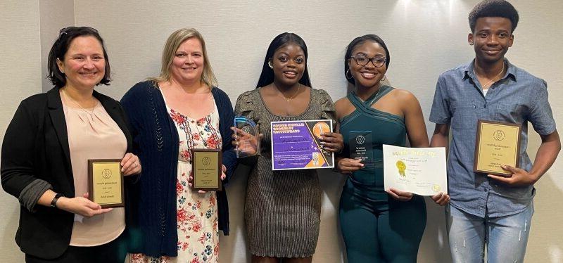 5 people smiling at camera and holding awards